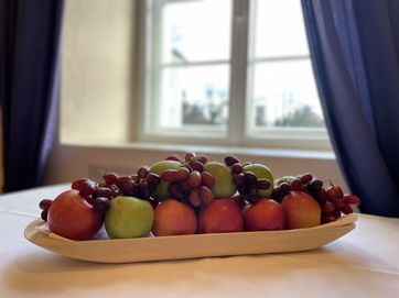 Äpfel und Trauben liegen in einer Schale auf einem Tisch.